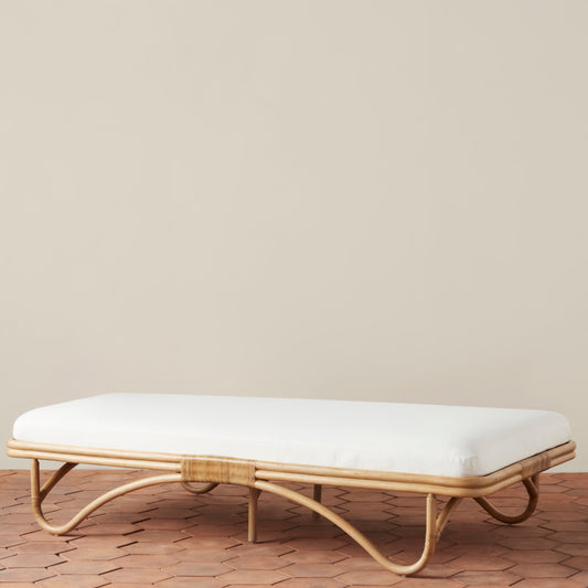 brown and white daybed with rattan legs on a tiled floor 