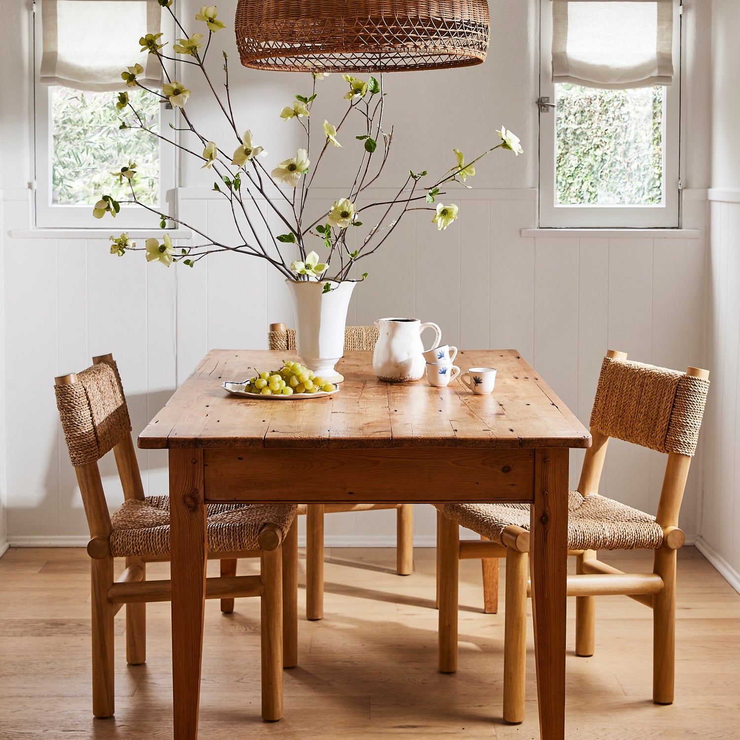 Dining room with wooden table and chairs, wicker pendant light, and decorative elements.- Number 2