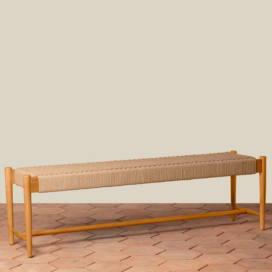 Beige bench with woven seat on a wooden floor against a beige wall