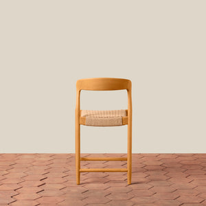 Wooden bar stool with woven seat on a wooden floor and beige wall background - Number 5