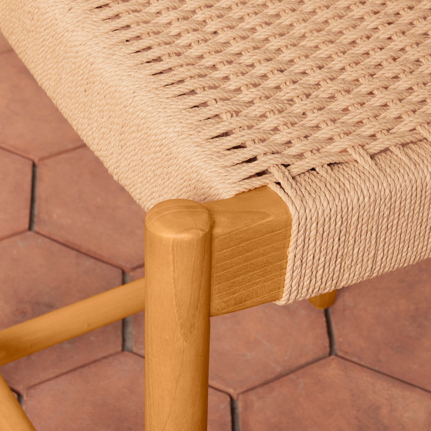 Close-up of a woven chair seat with wooden armrest on a tiled floor background- Number 7