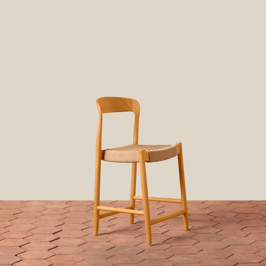 Wooden bar stool with woven seat on a wooden floor and beige wall background