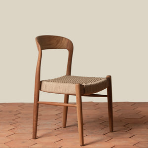 Wooden chair with woven seat on a wooden floor and beige wall background - Number 1