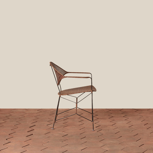 brown rattan and iron chair with pointed legs on tile floor against white background - Image 2