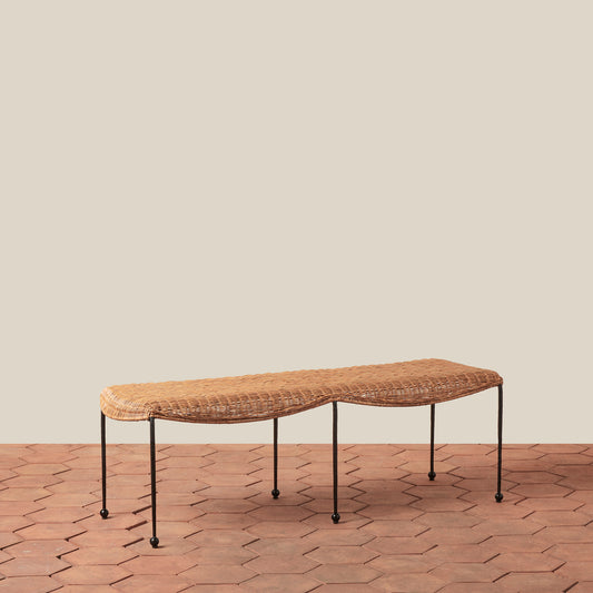 rattan and iron bench on tiled floor against white background