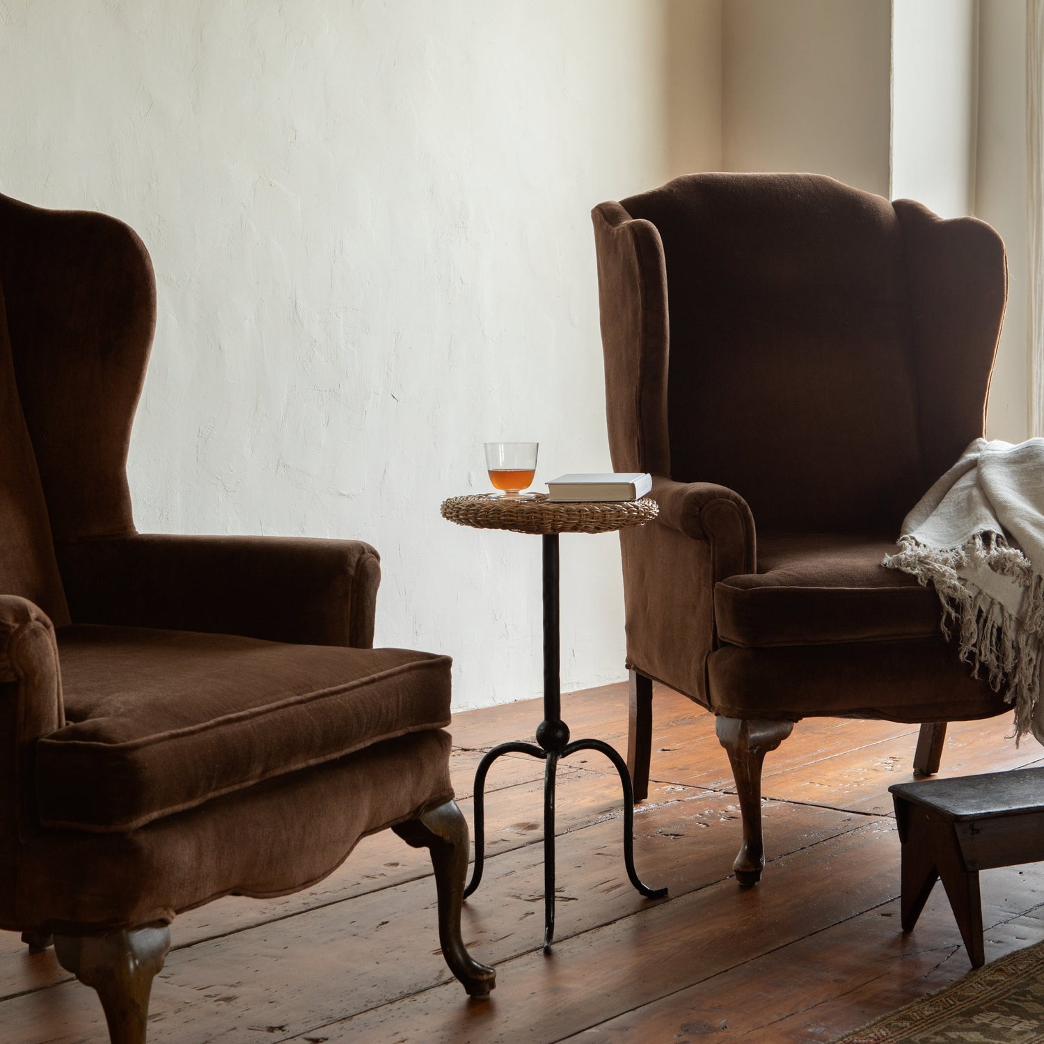 Two brown armchairs in a room with a small table and a blanket.- Number 3