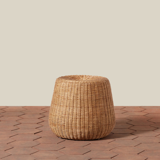 Woven brown stool on a wooden floor with a neutral background