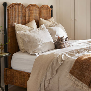 Bedroom with a bed featuring white pillows and a brown blanket, next to a nightstand. - Number 2