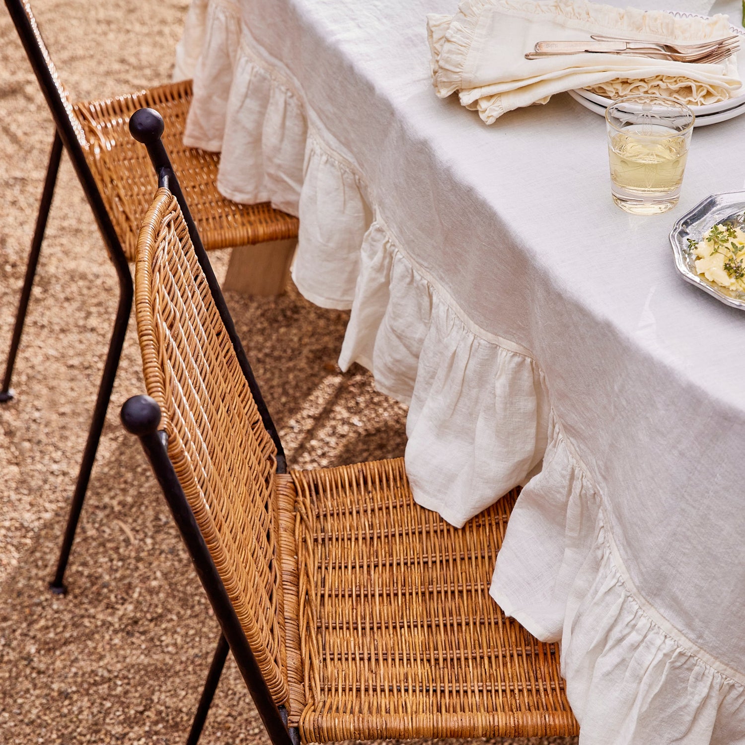 Outdoor table setting with a white tablecloth and wicker chair.- Number 3