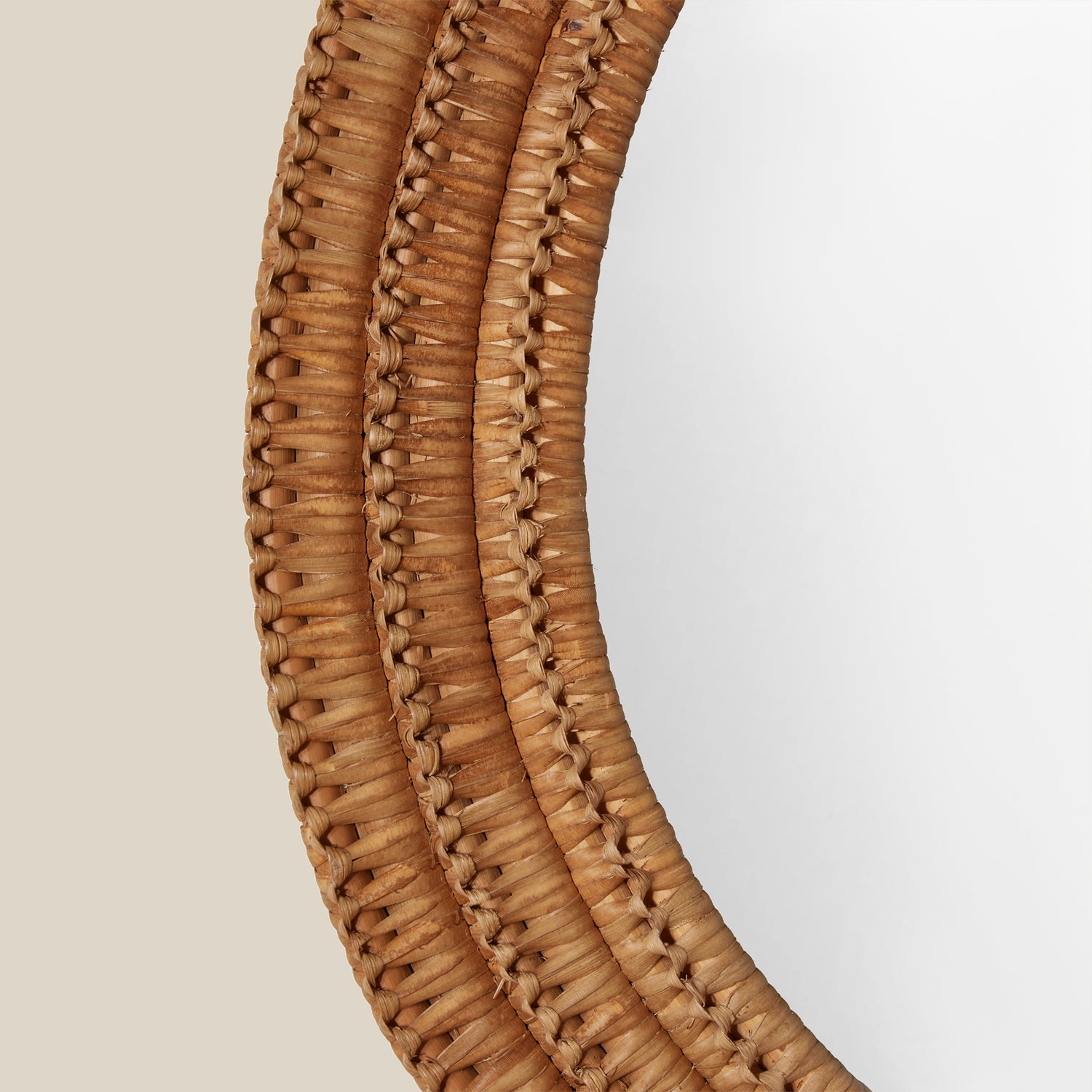 Close up of a round mirror with a woven wicker brown frame on a beige wall- Number 5