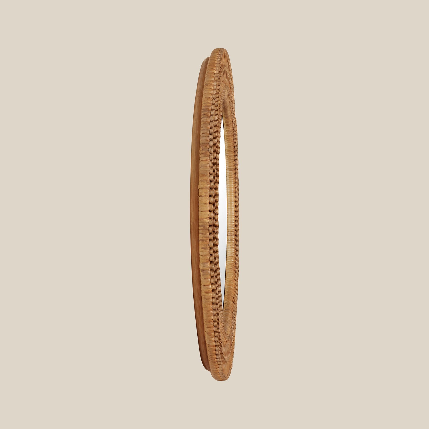 Side view of a round mirror with a woven wicker brown frame on a beige wall- Number 4