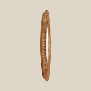 Side view of a round mirror with a woven wicker brown frame on a beige wall - Number 4