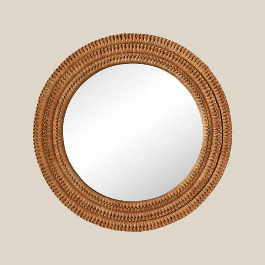 Round mirror with a woven wicker brown frame on a beige wall