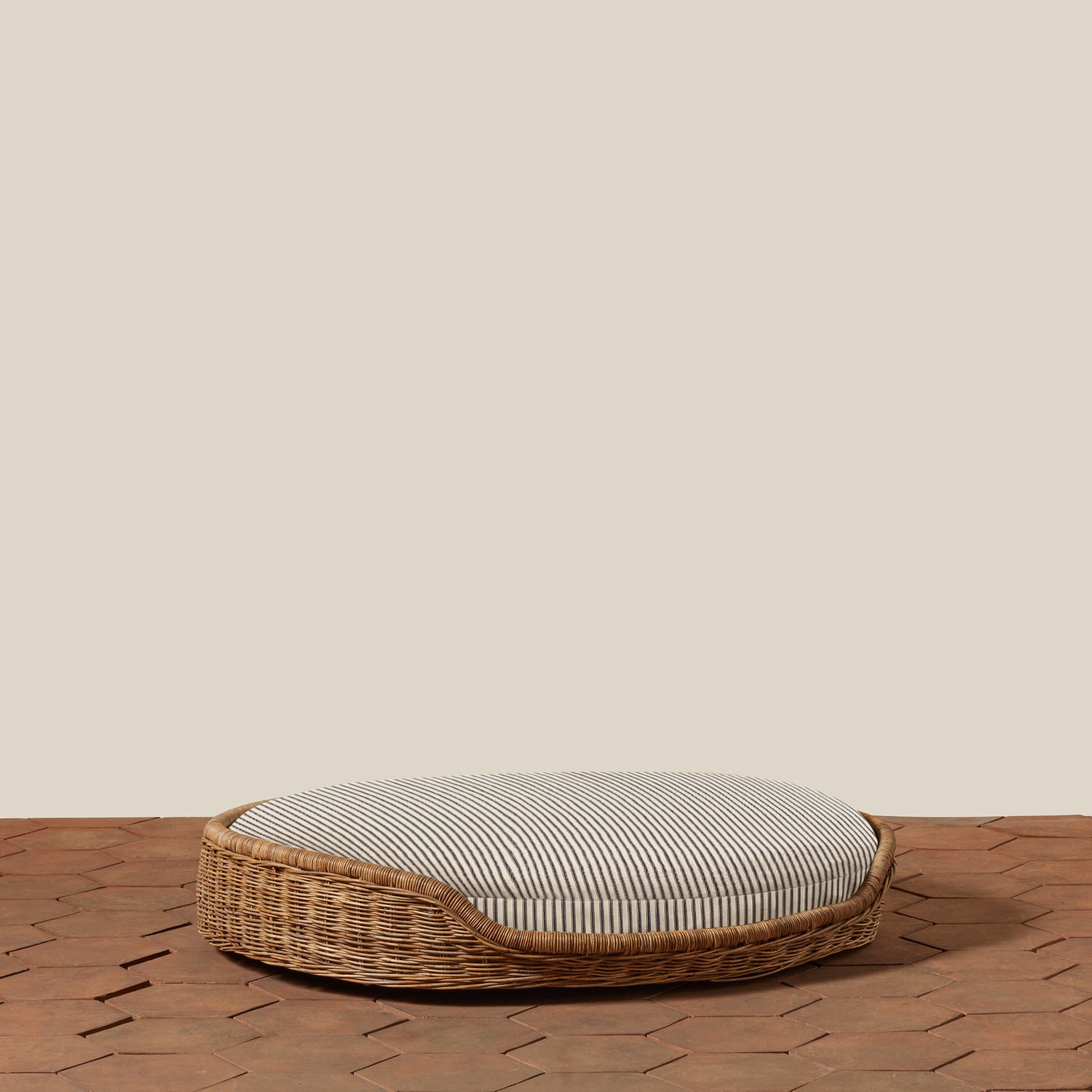 Wicker pet bed with striped cushion on a wooden floor.- Number 17