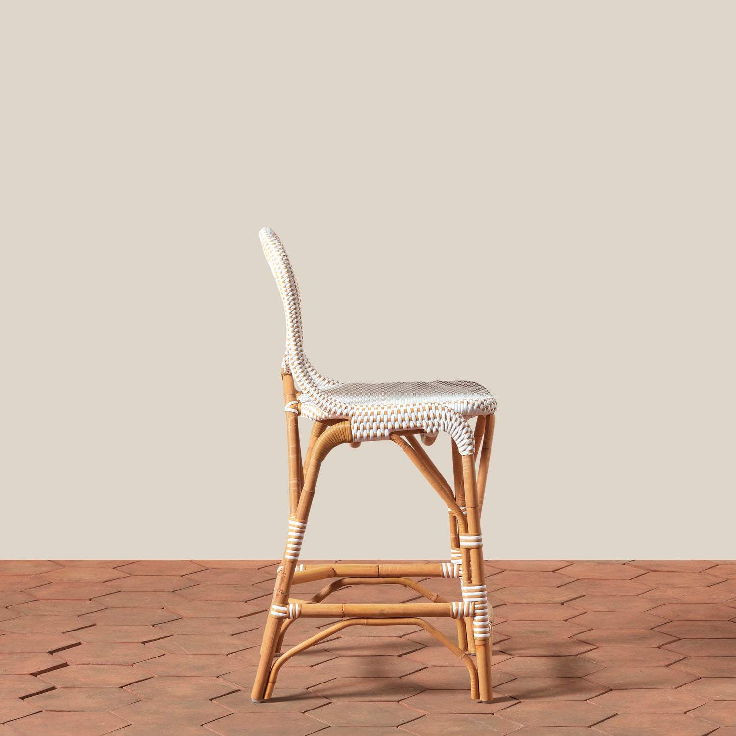 Wicker bar stool with woven seat on a wooden floor against a beige wall- Number 4