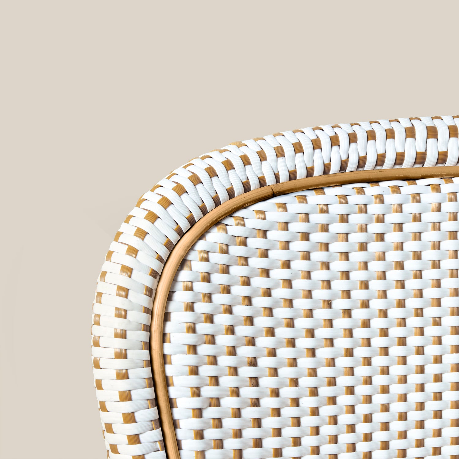 Close-up of a woven chair with white and brown pattern on a wooden floor.- Number 8