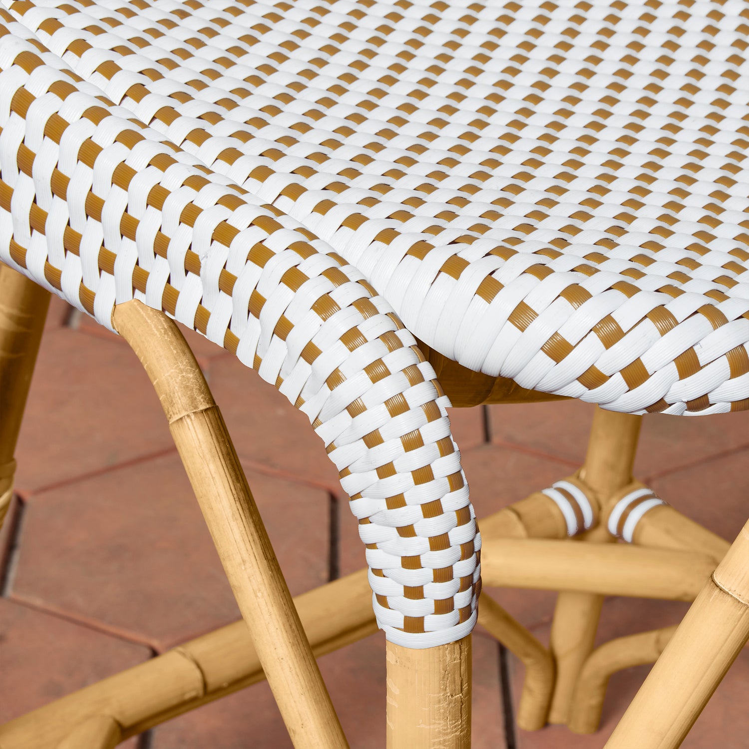 Close-up of a woven chair with white and brown pattern on a wooden floor.- Number 7