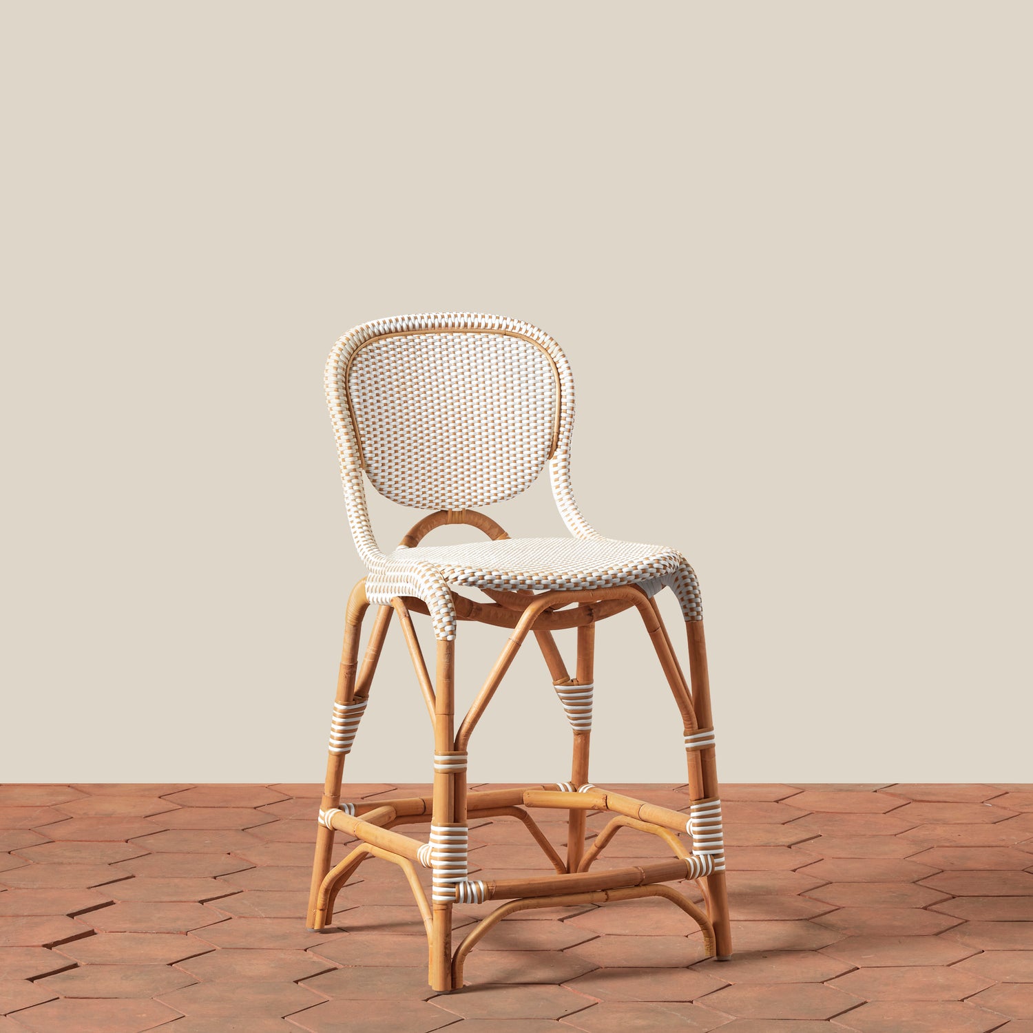 Rattan bar stool with woven backrest and seat on a wooden floor.- Number 1