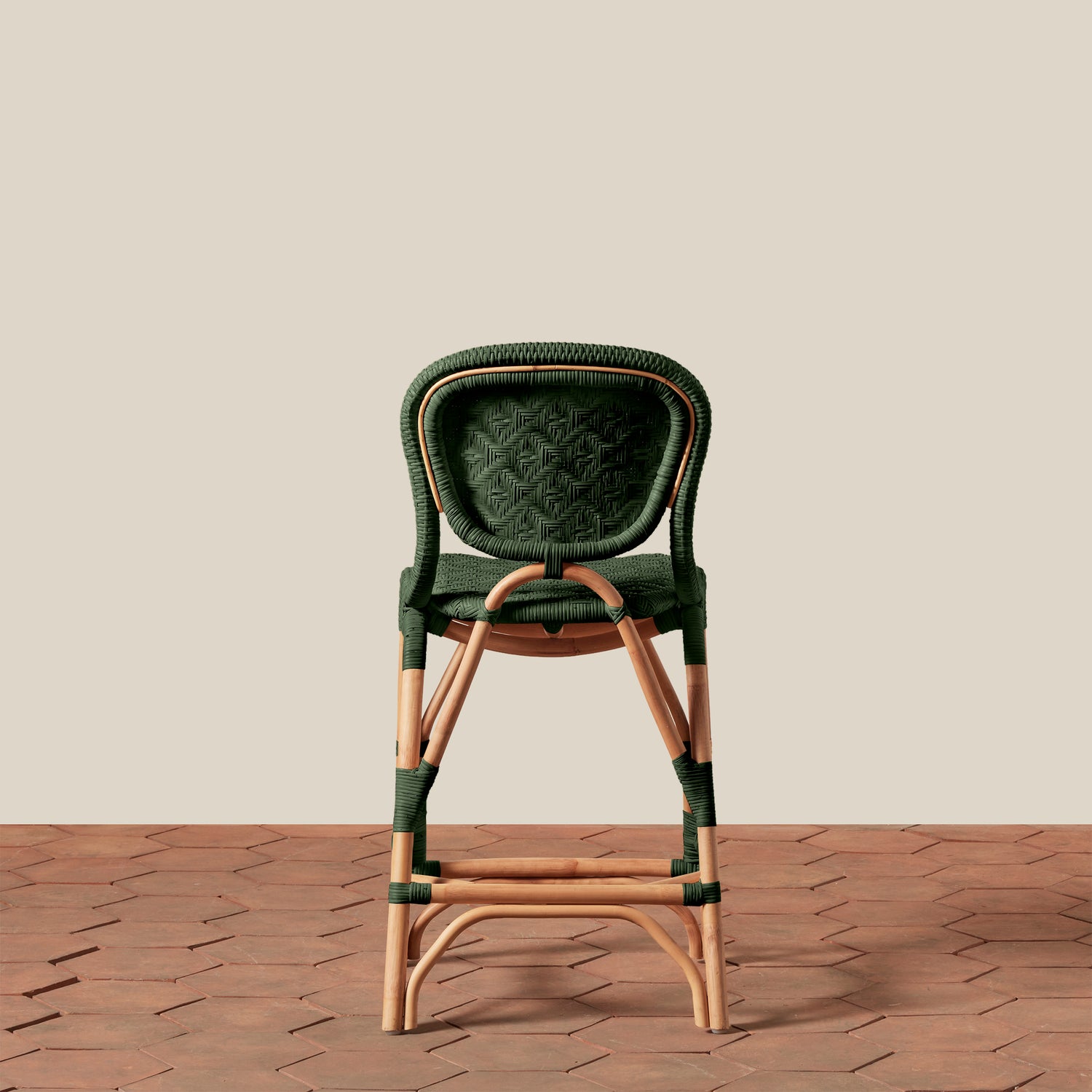 Green wicker bar stool on a wooden floor with a beige wall background- Number 18