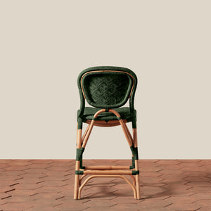 Green wicker bar stool on a wooden floor with a beige wall background - Number 18