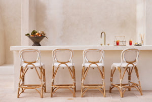 Four rattan bar stools in front of a white countertop with a neutral wall background. - Number 2