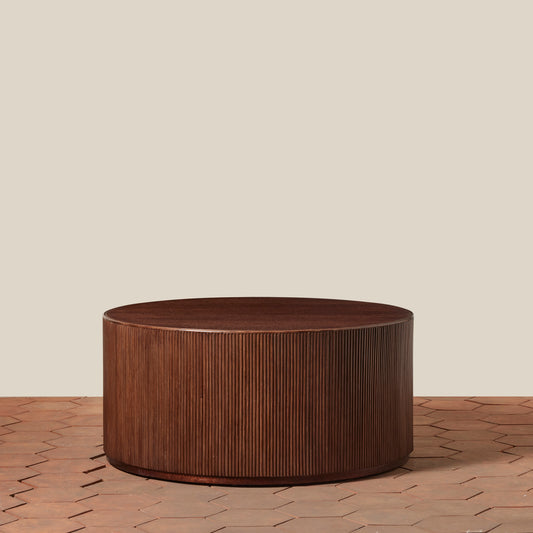 Wooden round coffee table on a wooden floor with a beige wall background