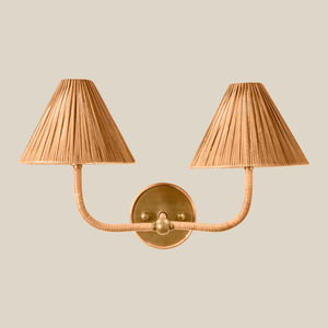 A two-light wall sconce with pleated beige shades and a polished brass wall mount and curved arms, shown against a solid light beige background. - Number 2