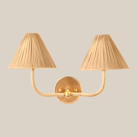 Gold wall sconce with two pleated lampshades on a beige background