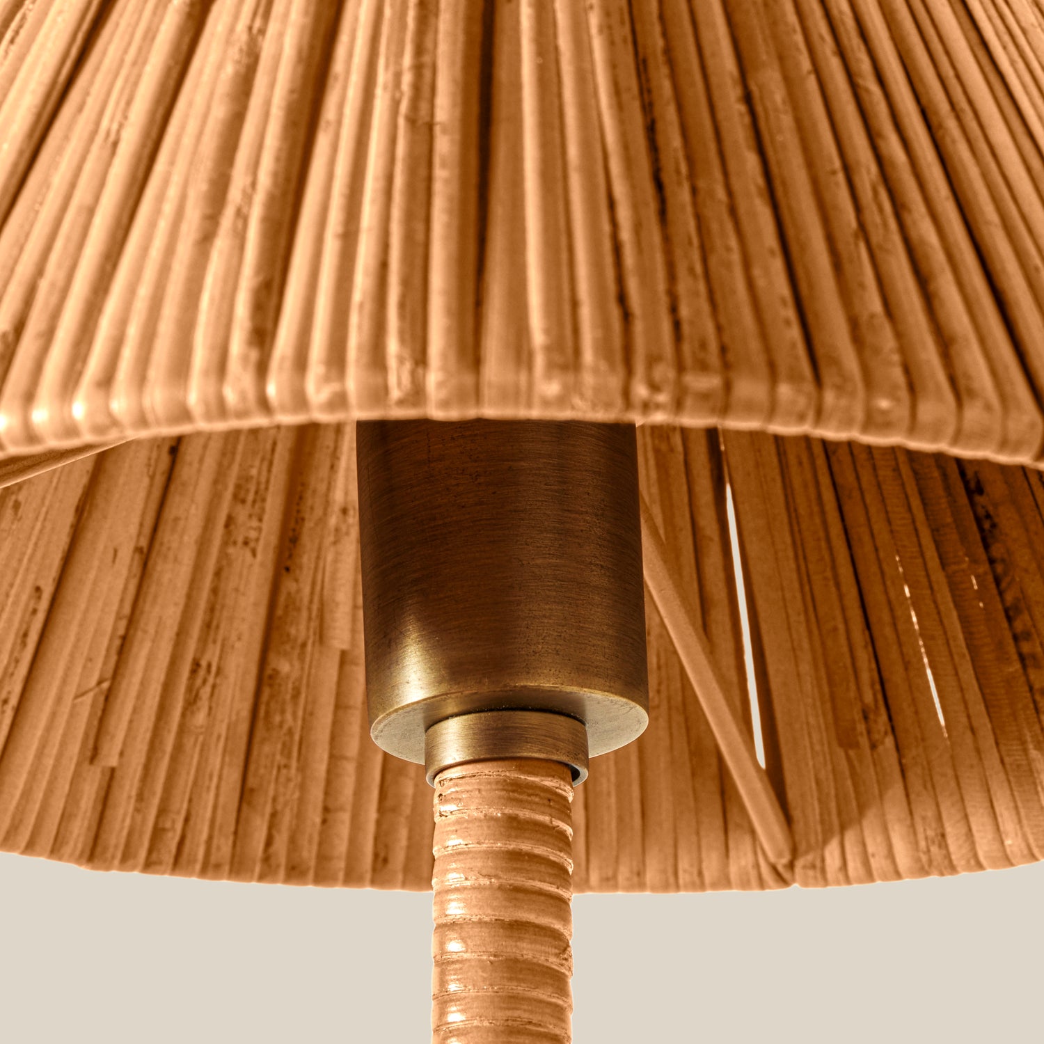 Close-up detail of a lampshade made of tightly bundled natural fibers, with a warm brass metal collar and matching textured stem visible against a light neutral background.- Number 4
