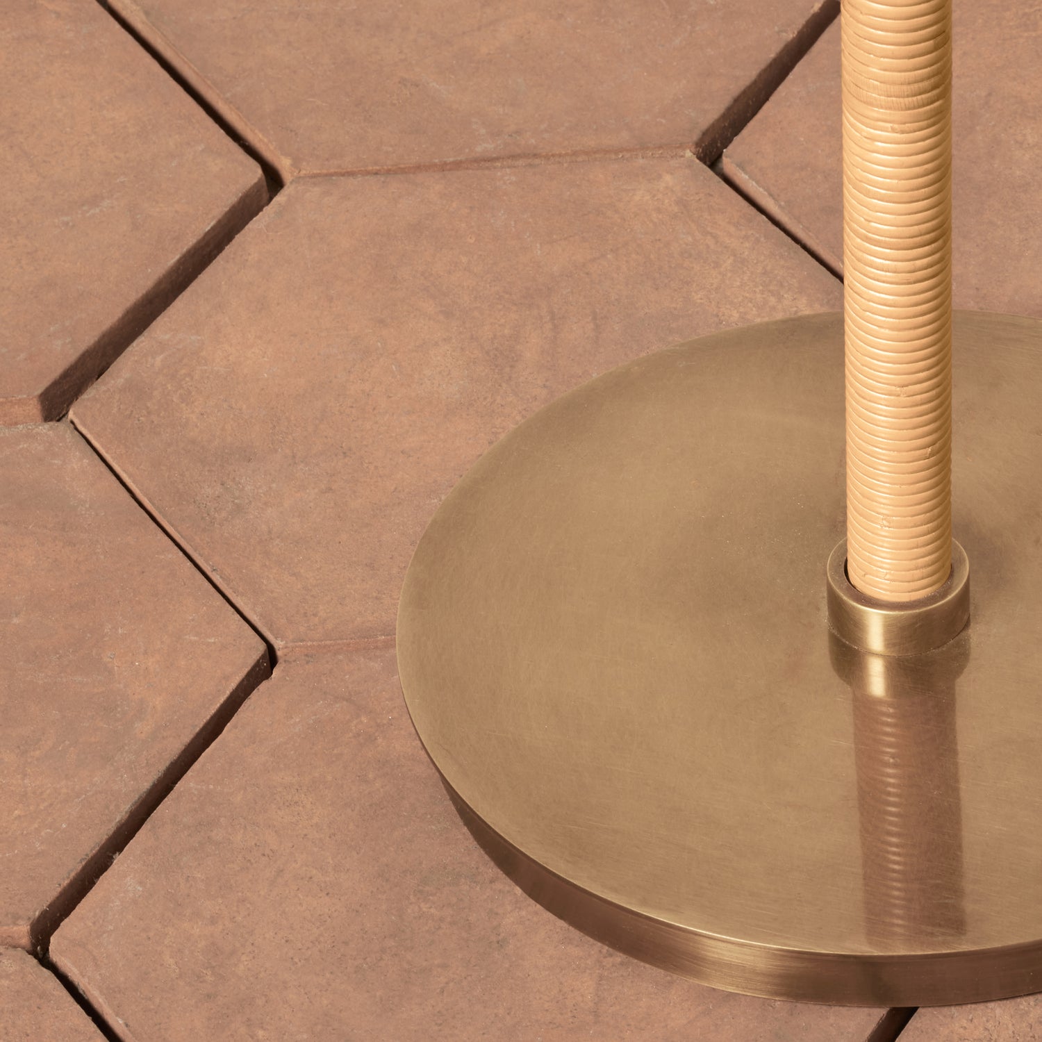 Closeup of a lamp base with a bronze base and rattan pole on a tile floor - Number 6