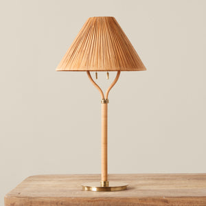 A rattan table lamp in a warm natural tan color, on a wooden table, against a plain light beige background. - Number 1