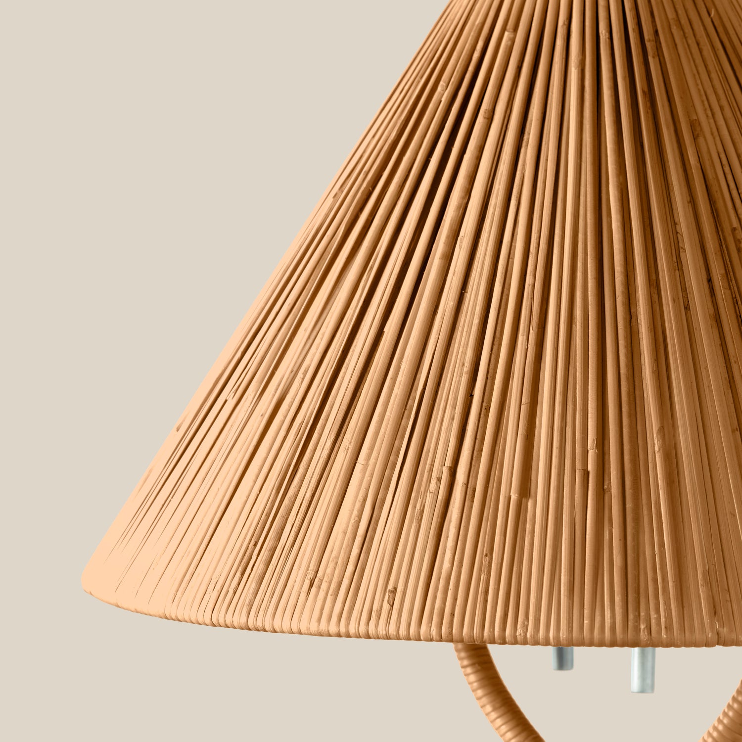 Close-up of a pleated conical lampshade in a warm natural tan color, with part of the lamp's cord and metal socket visible against a plain light beige background.- Number 3