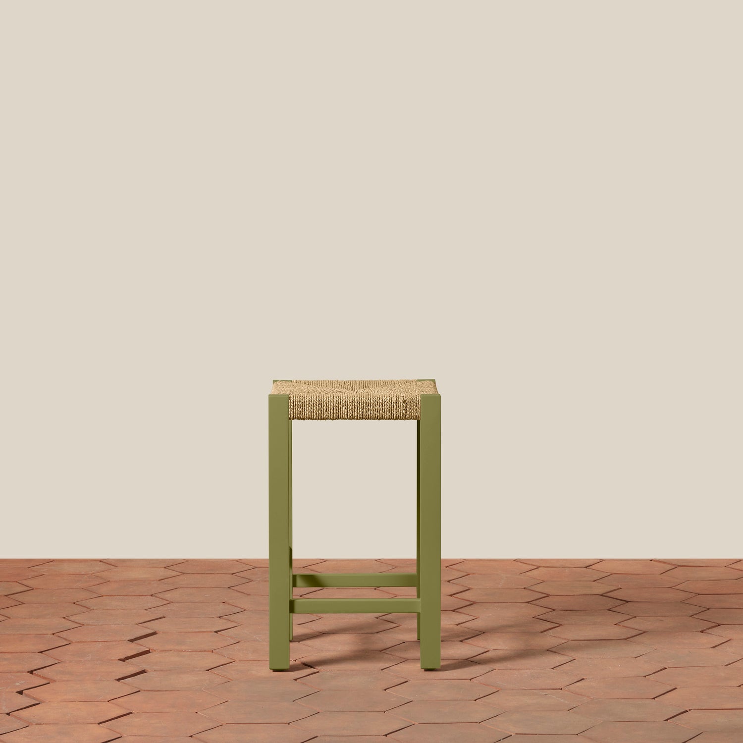 Green stool with woven seat on a wooden floor and beige wall background- Number 14