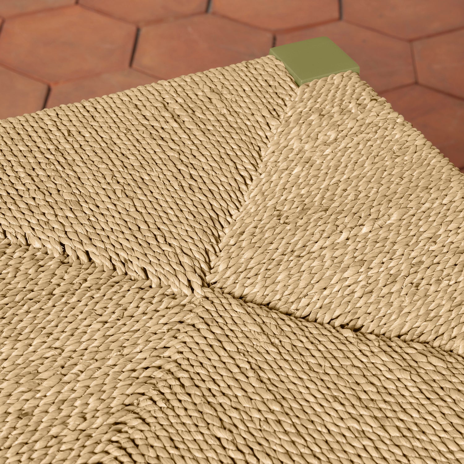 Close-up of a textured beige counter stool with a geometric pattern on a brown hexagonal tile floor.- Number 15
