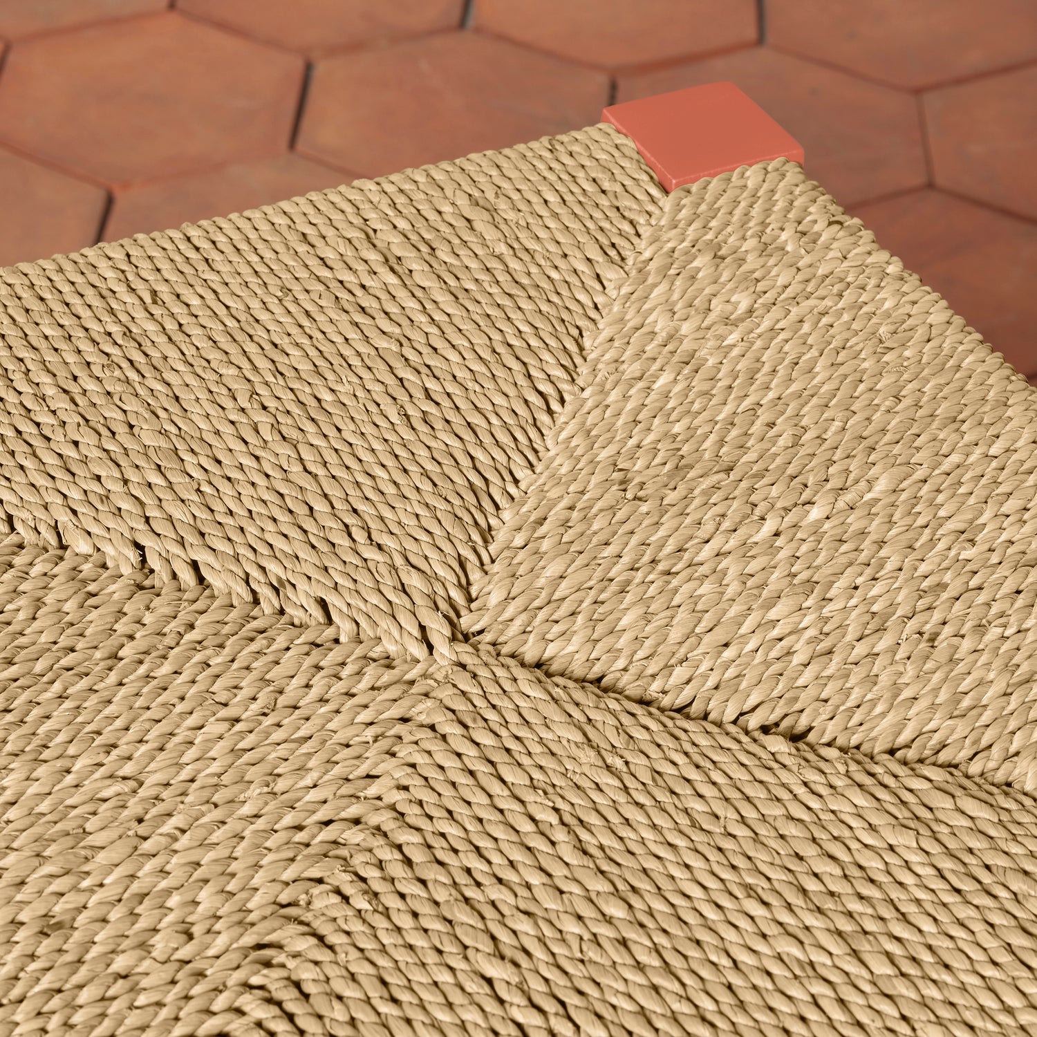 Close-up of a textured counter stool seat with a geometric pattern on a brown hexagonal tile floor.- Number 3