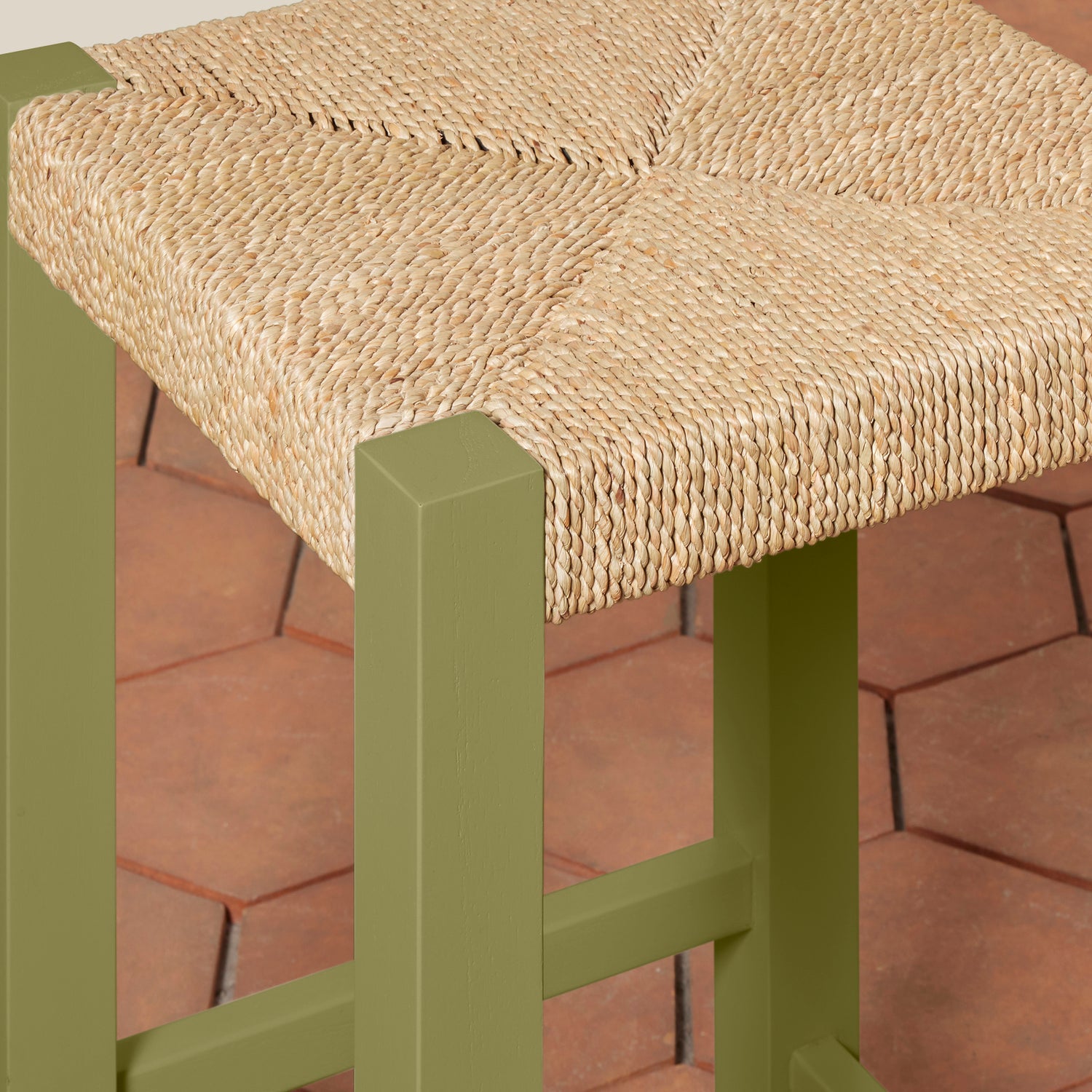 Green stool with woven seat on a red brick surface- Number 16