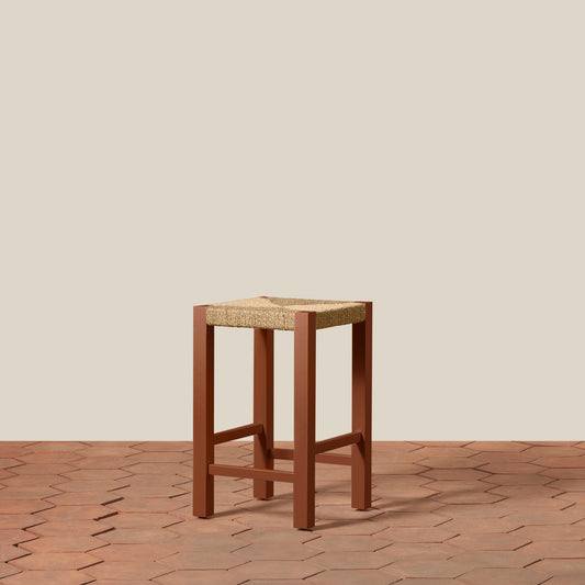 Wooden stool with woven top on a wooden floor and beige wall background