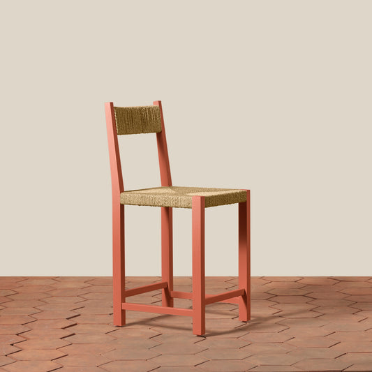 Wooden bar stool with woven seat and backrest on a wooden floor.