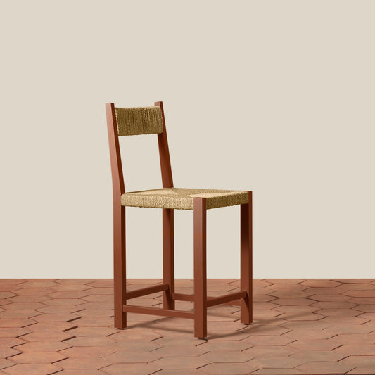 Wooden bar stool with woven backrest and seat on a wooden floor.