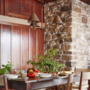 dark rattan chandelier against wood wall and stone fireplace, above table setting - Number 2