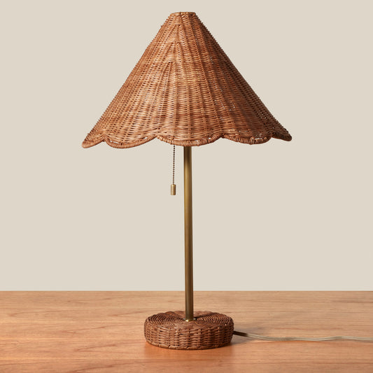 Wicker table lamp with scalloped shade on a wooden surface