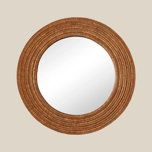 Round mirror with a woven brown frame on a beige wall