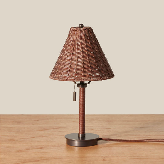 Wicker table lamp with brown shade on a wooden surface