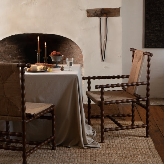 Dining room with rustic fireplace, wooden chairs, and a table set for a meal. - Image 2