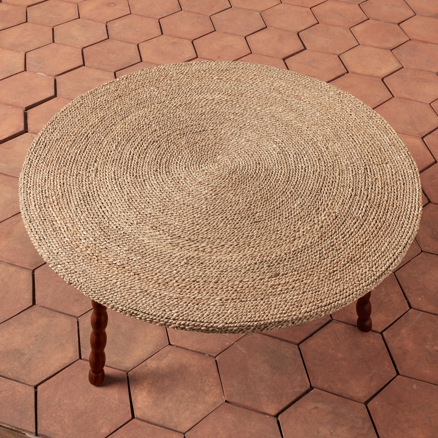 Round woven stool on a hexagonal brick-patterned patio- Number 3