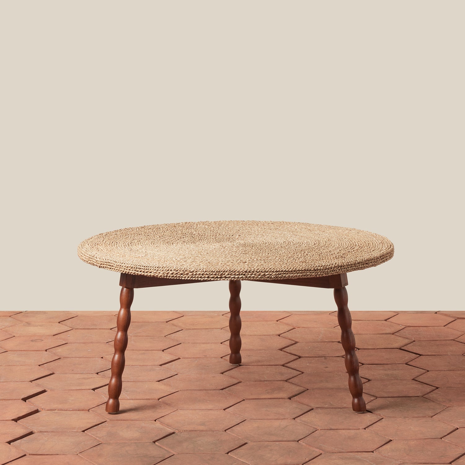 Round woven table with wooden legs on a wooden floor.- Number 1