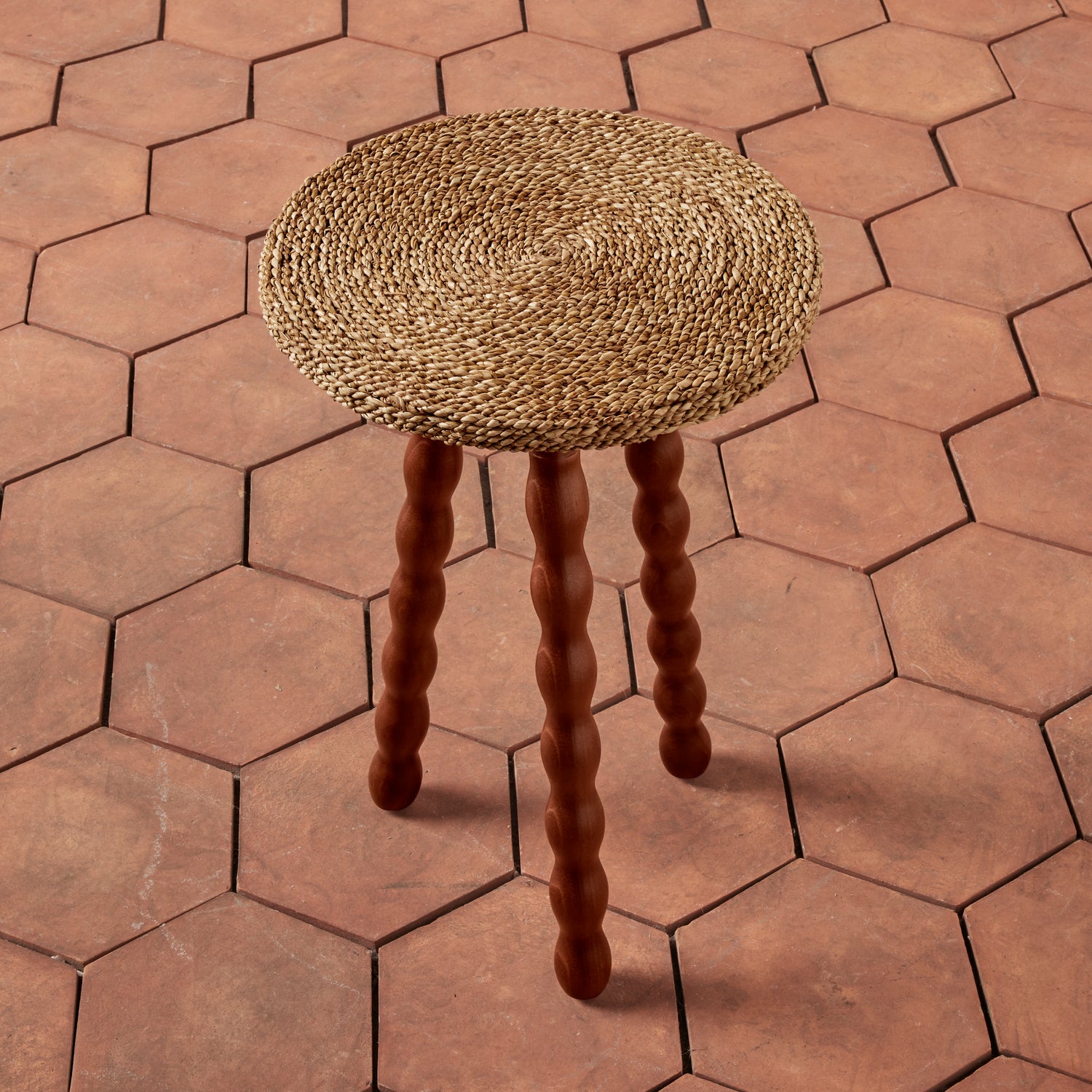 Round woven stool on a hexagonal tile floor- Number 3