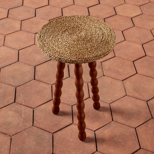 Round woven stool on a hexagonal tile floor - Number 3