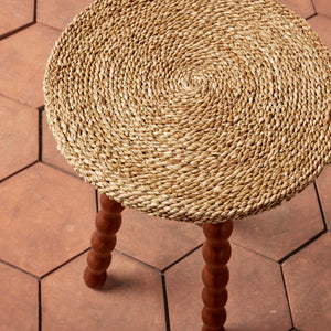 Round woven stool with wooden legs on a hexagonal tiled floor - Number 4