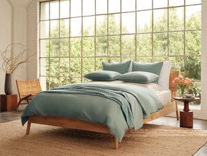 Bedroom with wooden bed, green bedding, and large windows. - Number 4